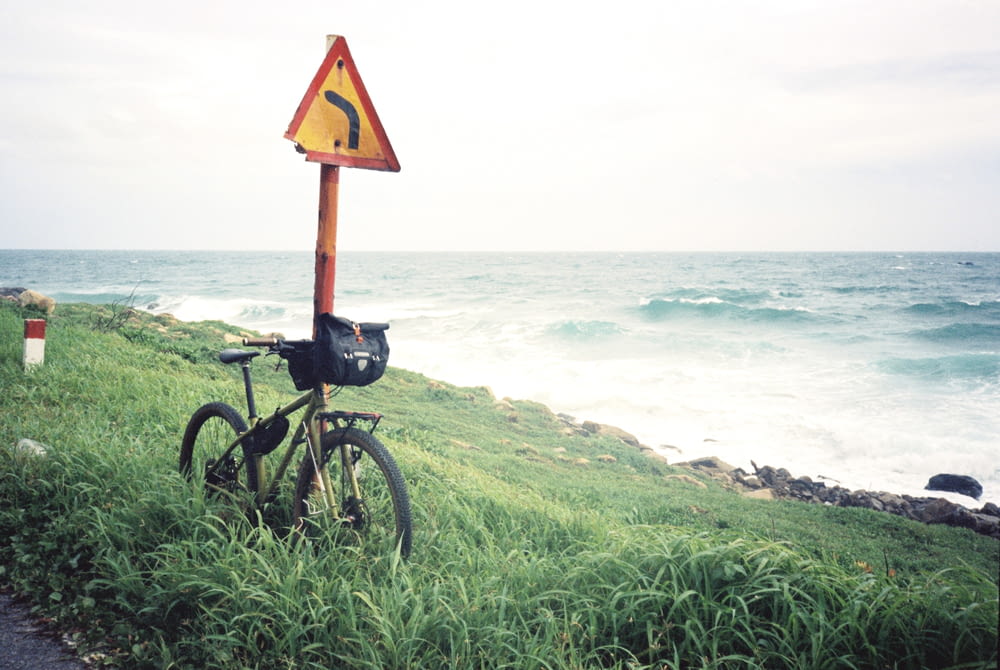 una bicicleta apoyada contra un letrero al costado de una carretera