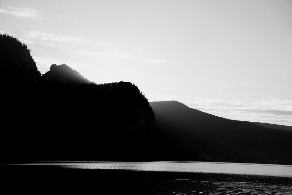a black and white photo of a mountain and a body of water