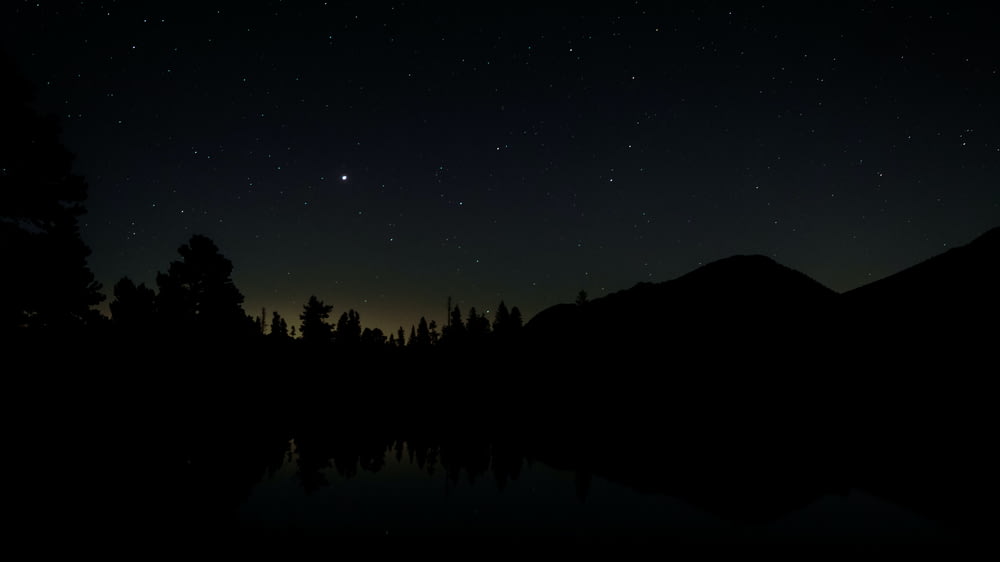the night sky is reflected in the still water of a lake