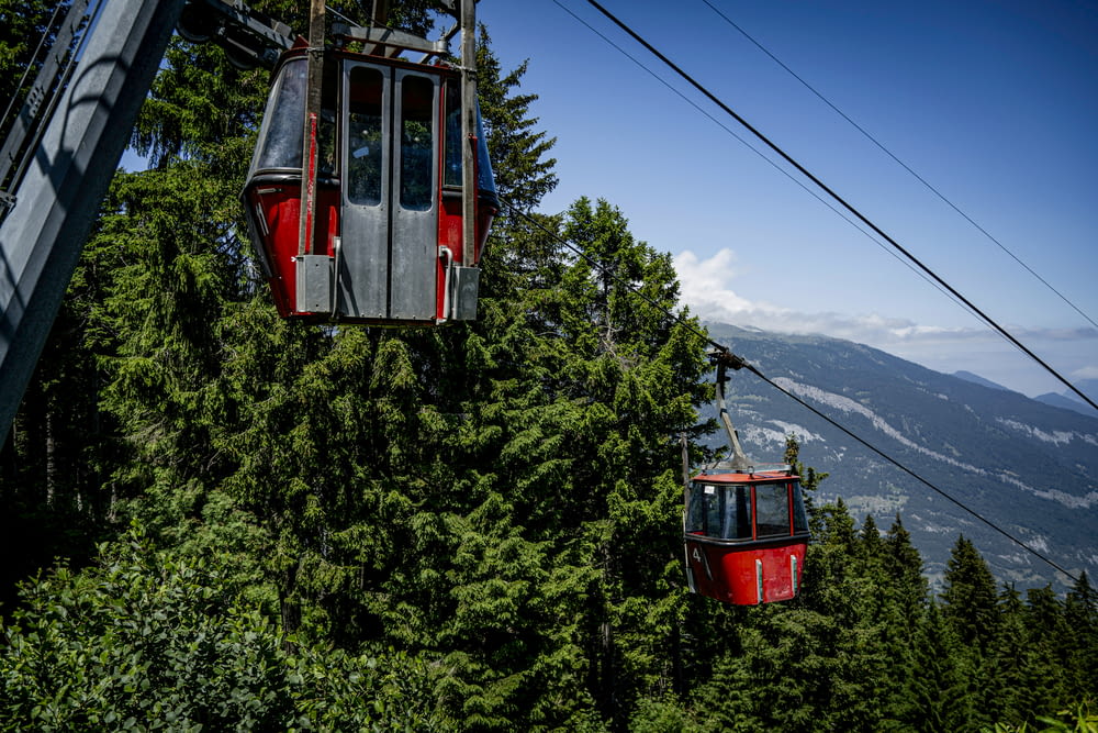 a couple of people riding a ski lift over a forest