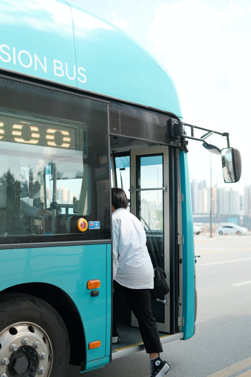 a woman getting off of a blue bus