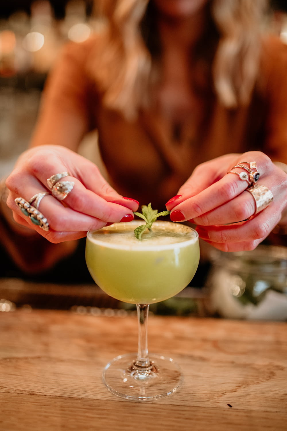 a woman holding a green cocktail in her hands