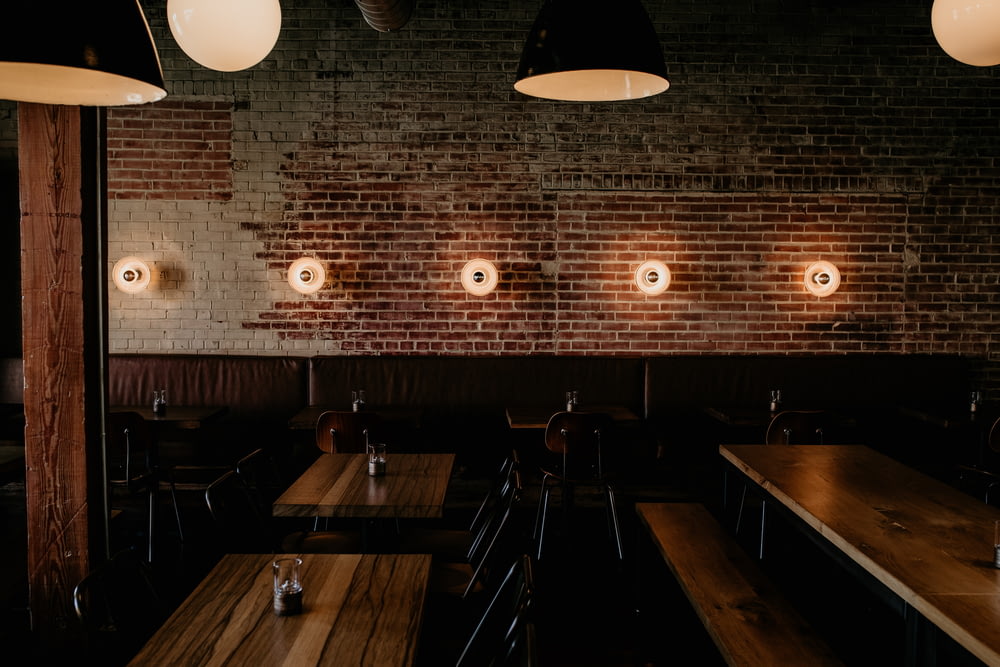 a row of tables in a restaurant with lights on the wall