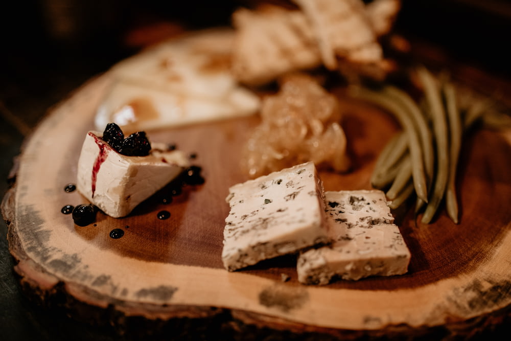a wooden plate topped with different types of cheese