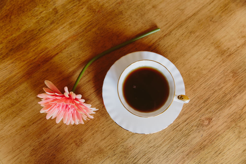 a cup of coffee and a flower on a table