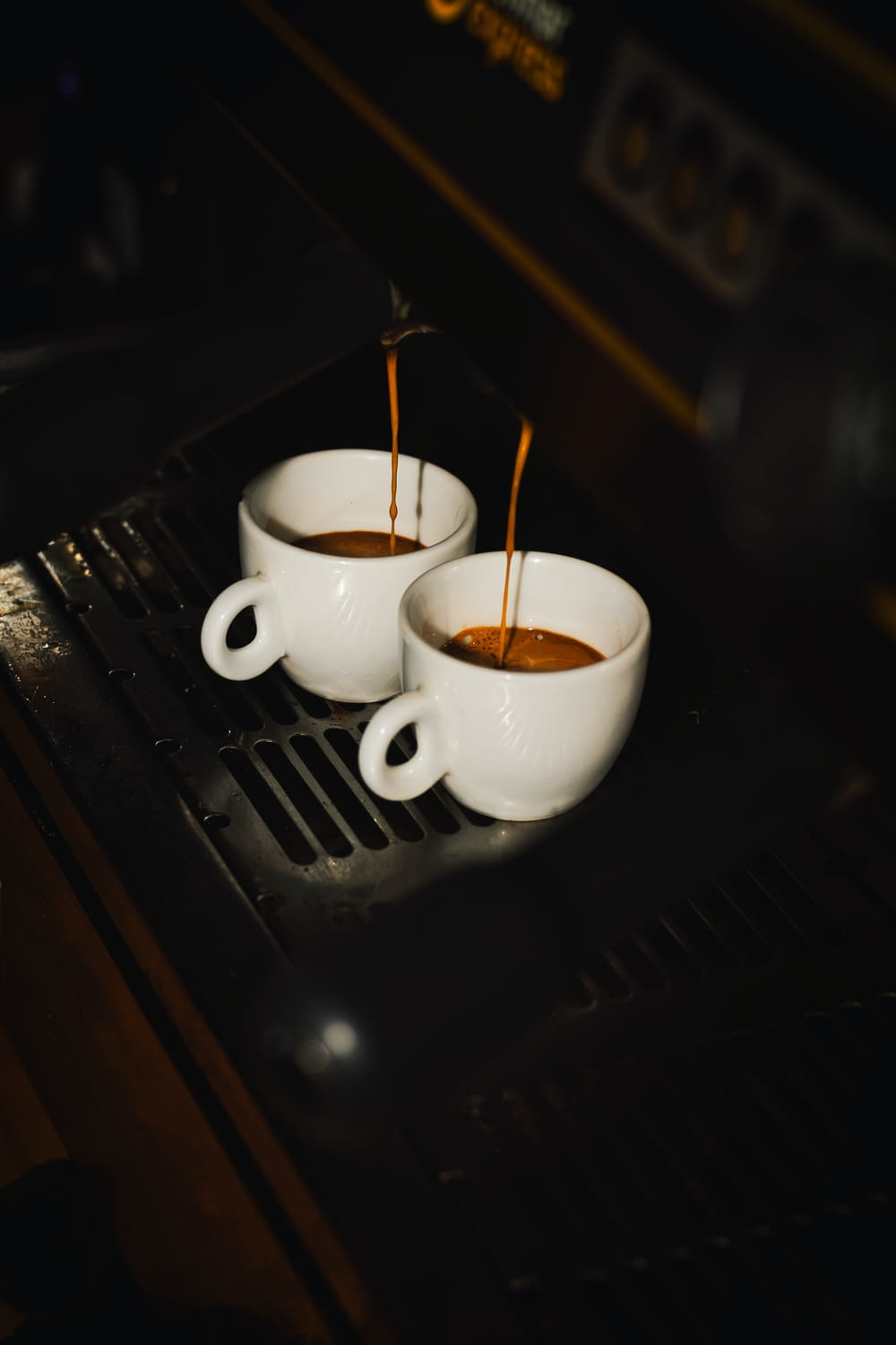 two white cups filled with liquid sitting on top of a stove