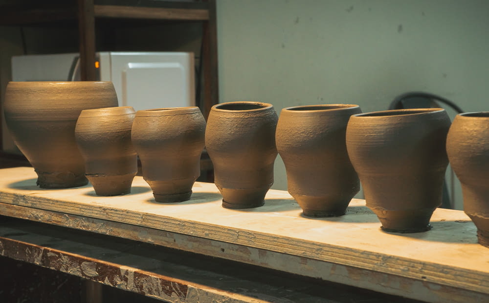 una fila di vasi di terracotta seduti sopra un tavolo