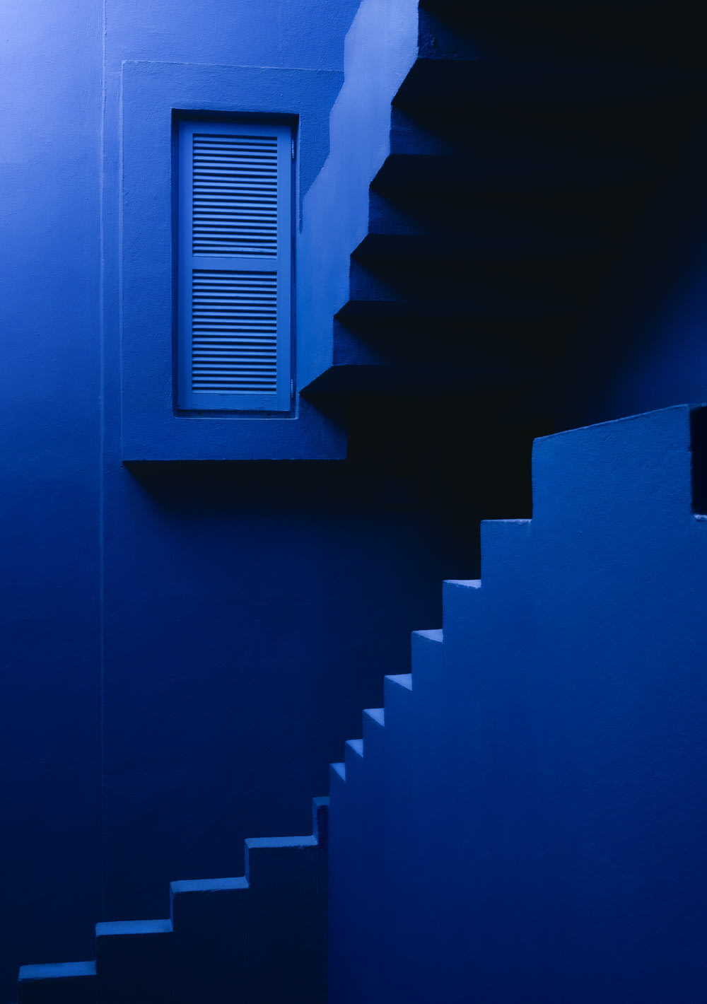 a blue staircase leading to a window in a building
