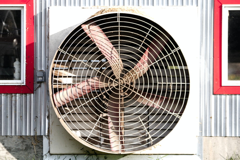 a large metal fan sitting on the side of a building