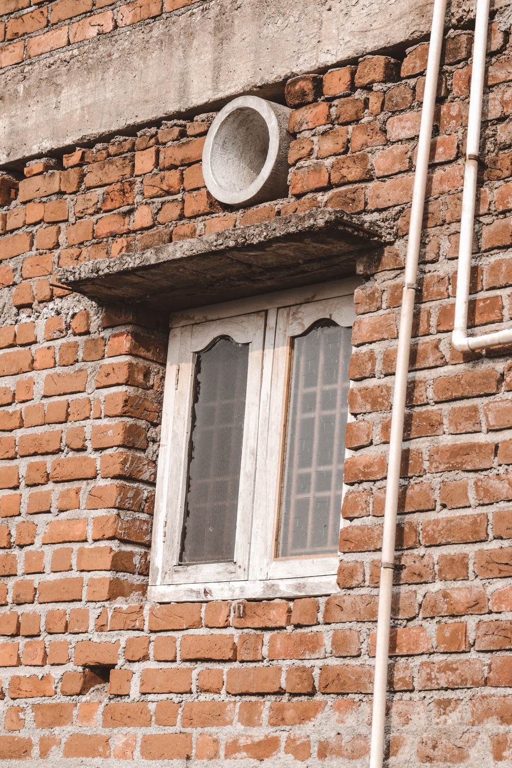a brick building with a window and a pipe