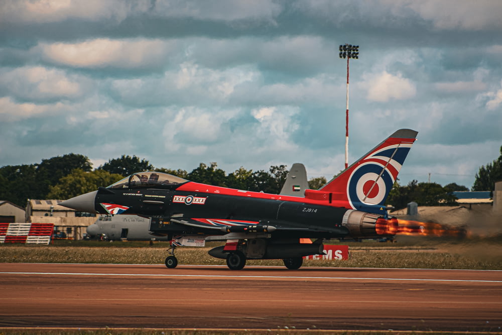 a red and black jet is on a runway