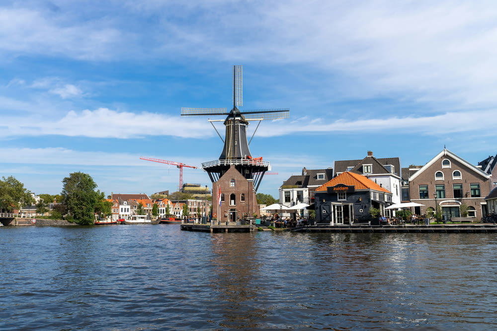 a windmill sitting on top of a river next to houses