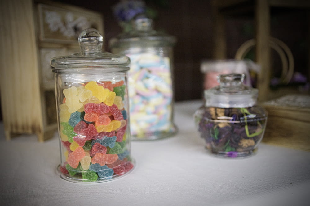 a glass jar filled with gummy bears sitting on top of a table
