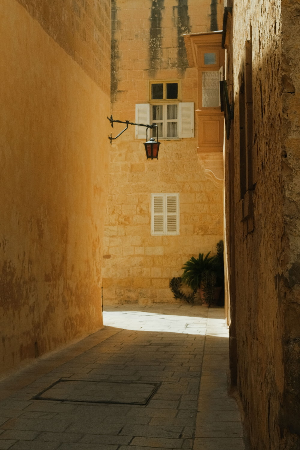 a narrow alley way with a lamp on the wall