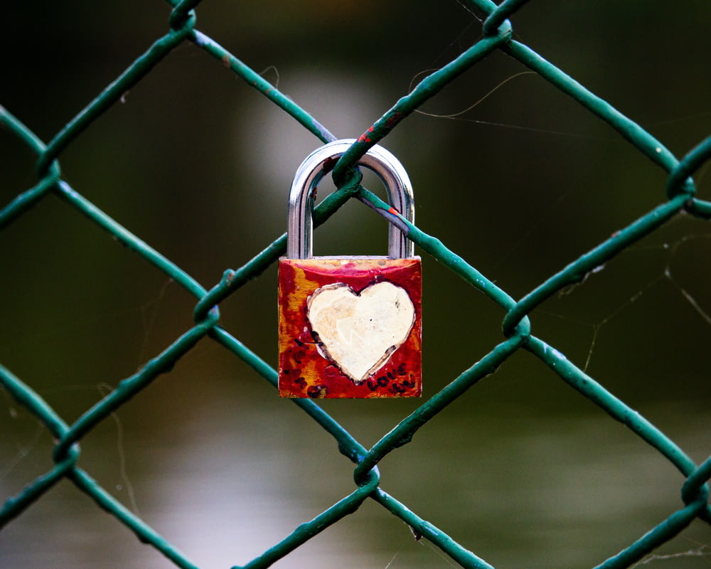a heart shaped padlock attached to a chain link fence