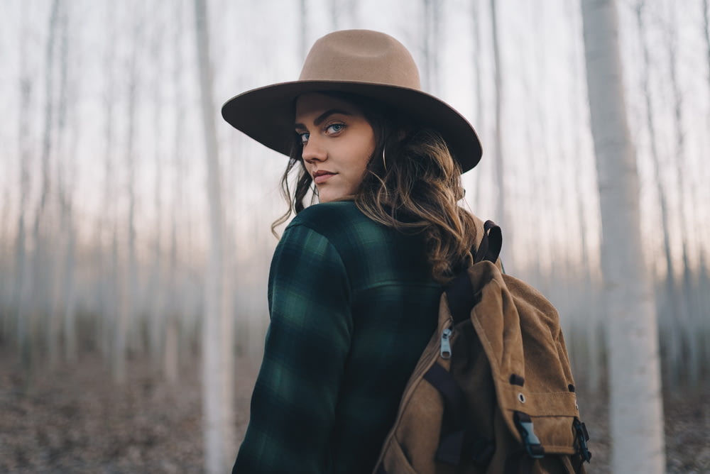 a woman wearing a hat in a forest