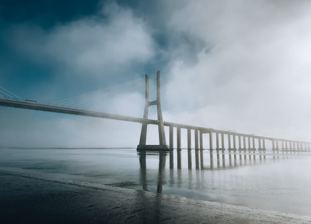 a long bridge over a body of water on a foggy day
