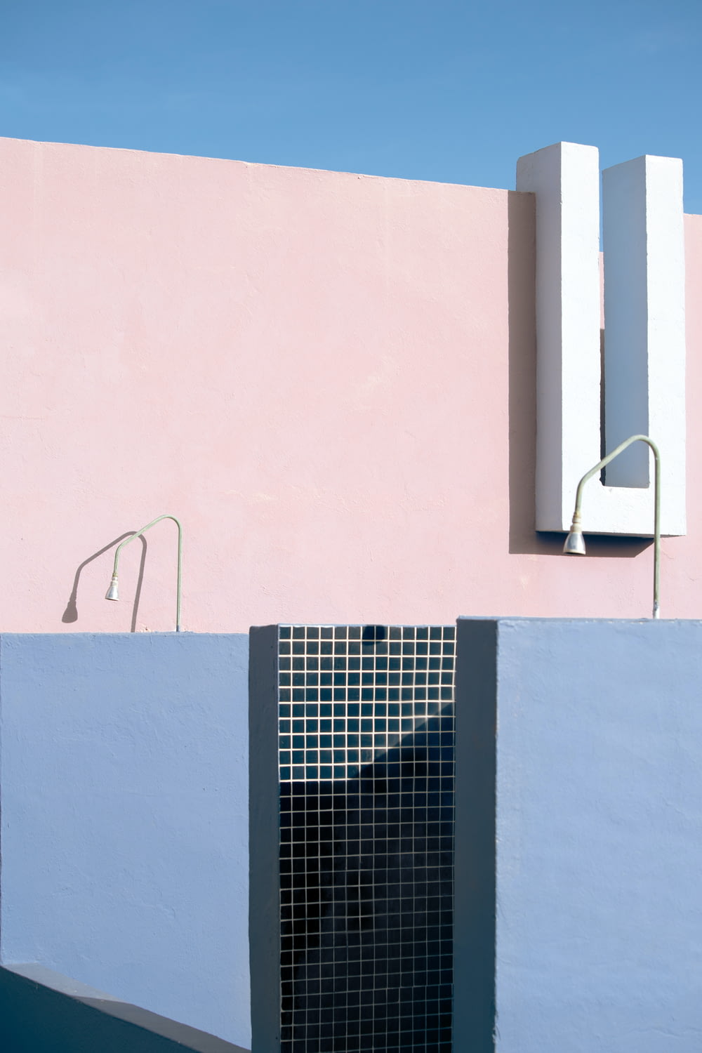 a blue and pink building with a black and white tiled pool