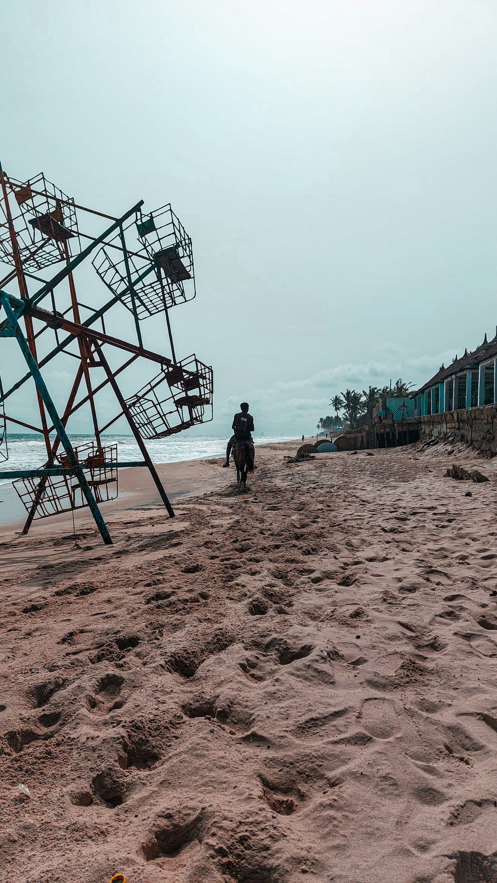 um homem caminhando em uma praia ao lado de uma torre de salva-vidas