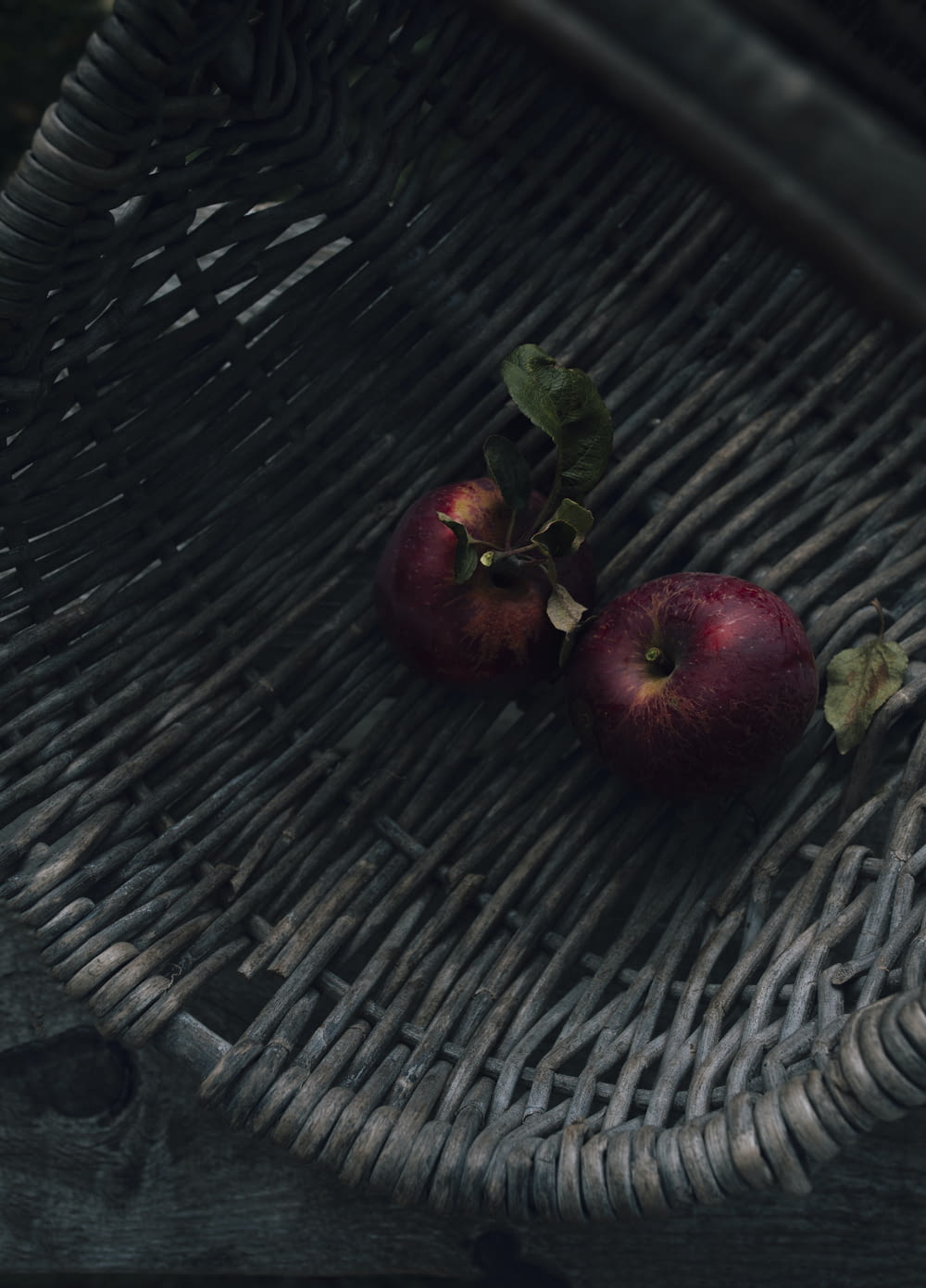 two apples sitting on top of a wicker basket