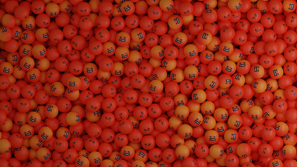 a large pile of oranges with faces drawn on them