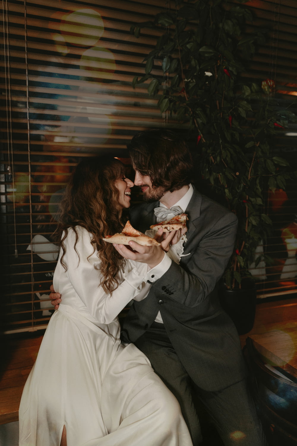 a bride and groom are sharing a slice of pizza