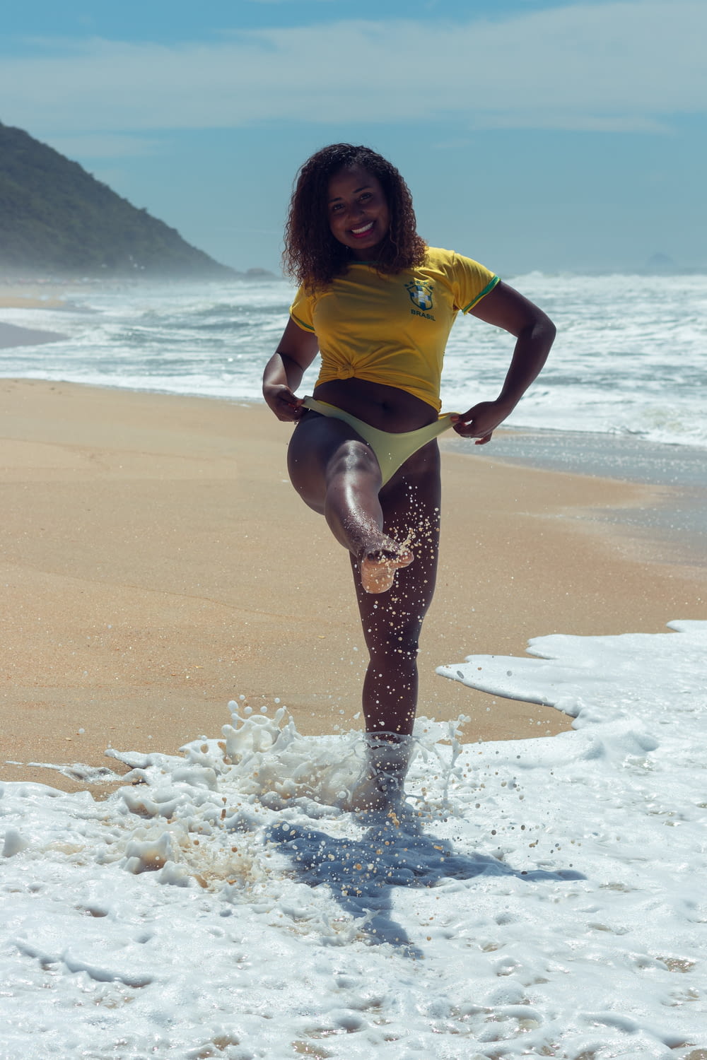 a woman in a yellow shirt is standing on the beach