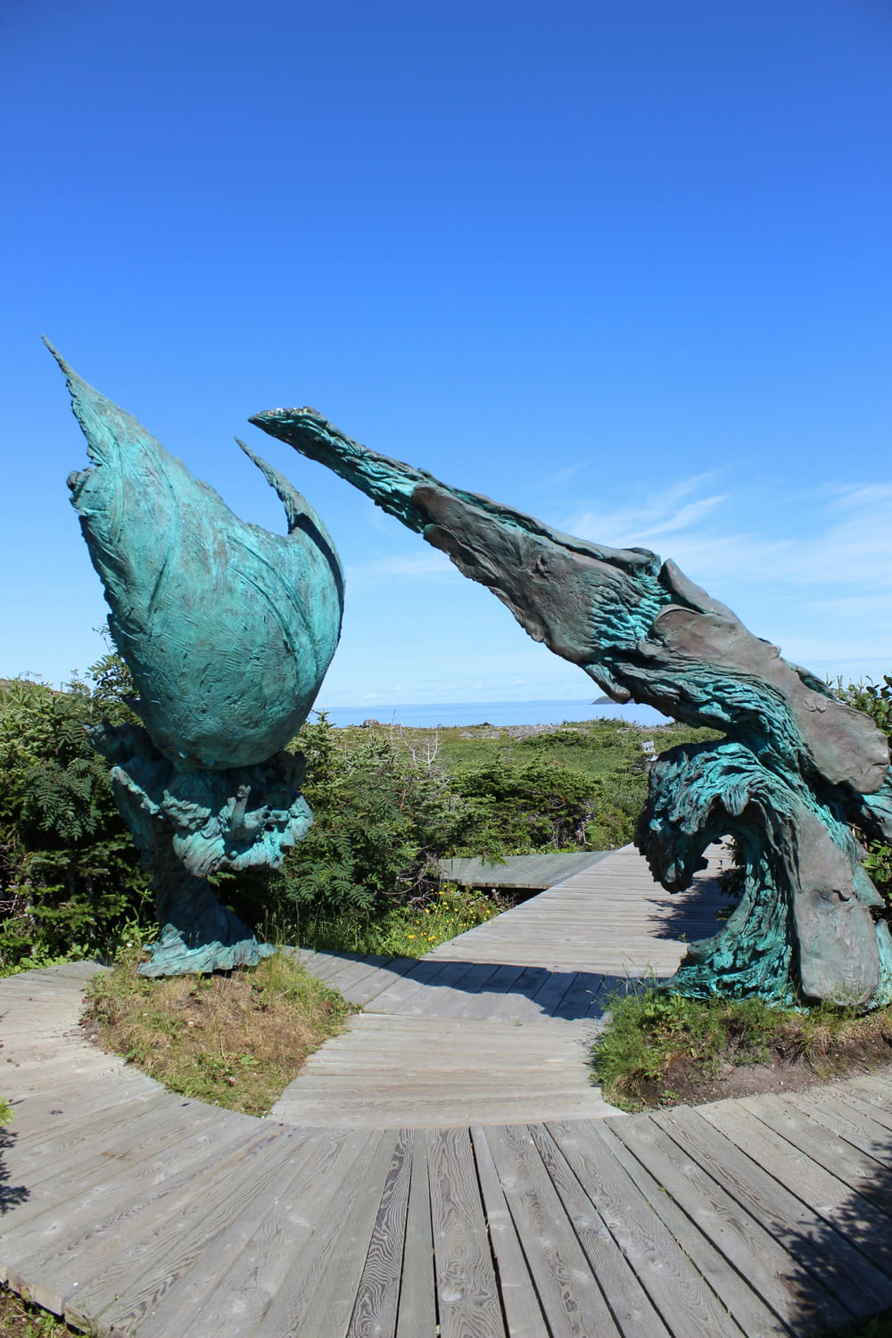 a statue of two birds on a wooden walkway