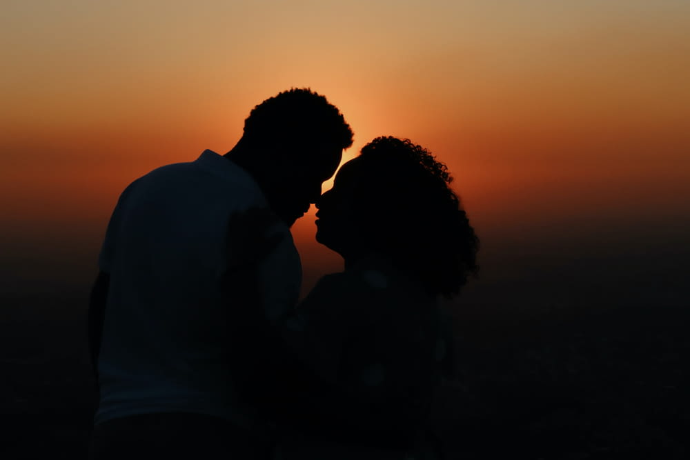 a silhouette of a man and a woman at sunset