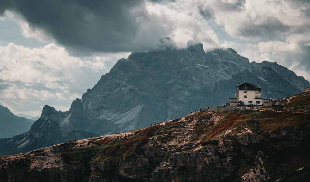 a house sitting on top of a mountain under a cloudy sky