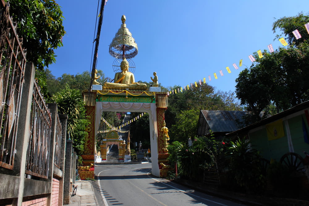 a large golden buddha statue sitting on top of a wooden gate