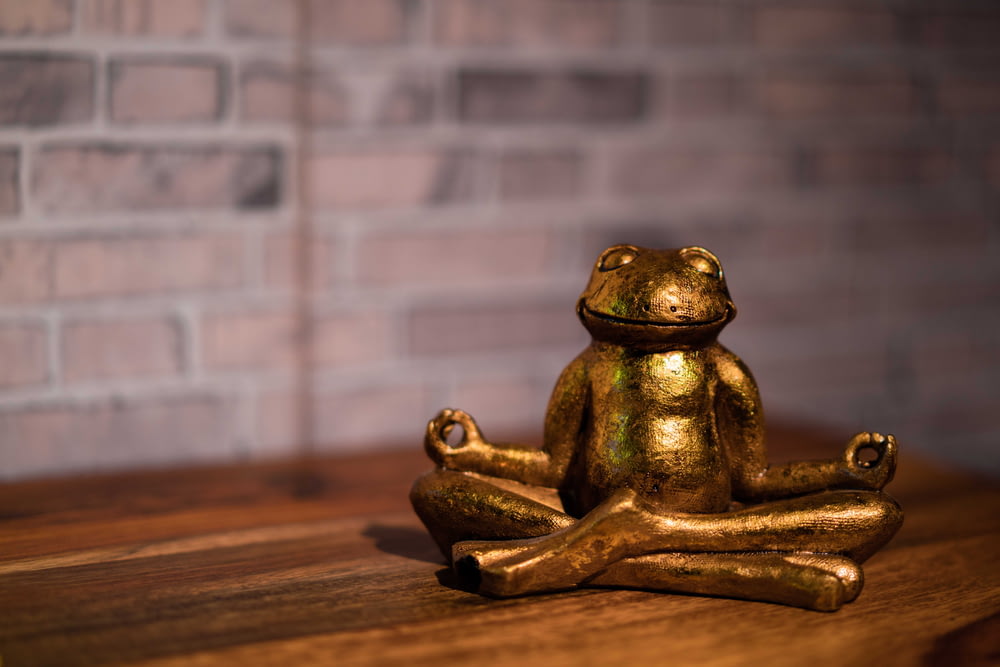 a gold frog statue sitting on top of a wooden table