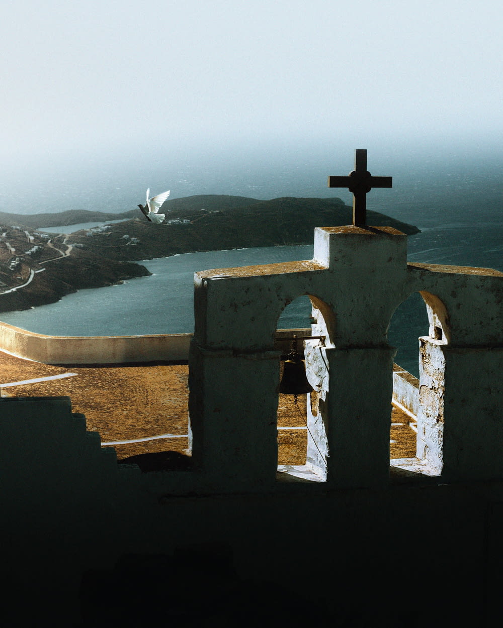 a cross on top of a building overlooking a body of water
