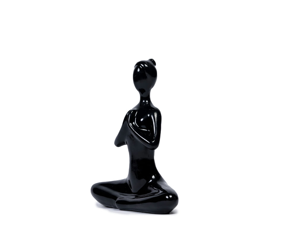 a black figurine sitting on a white surface