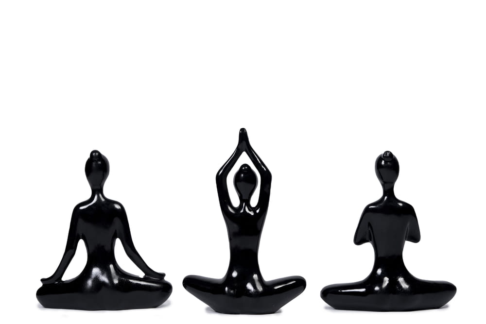 three black figurines of a person doing yoga