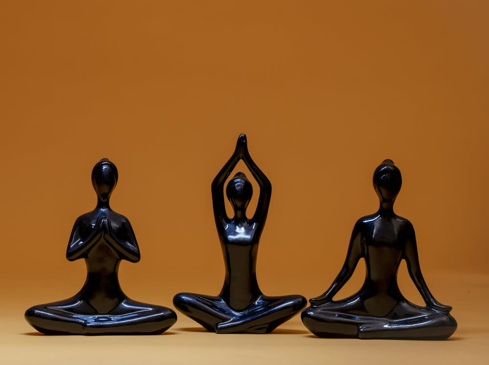 a group of three statues of people doing yoga