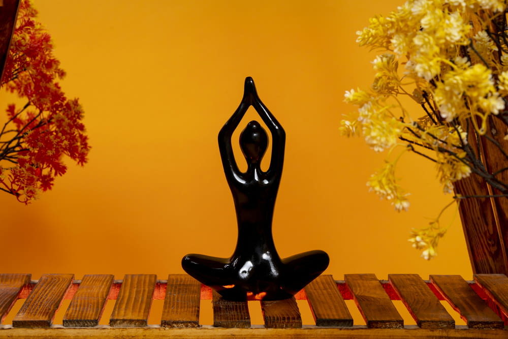 a statue of a person doing yoga on a wooden table
