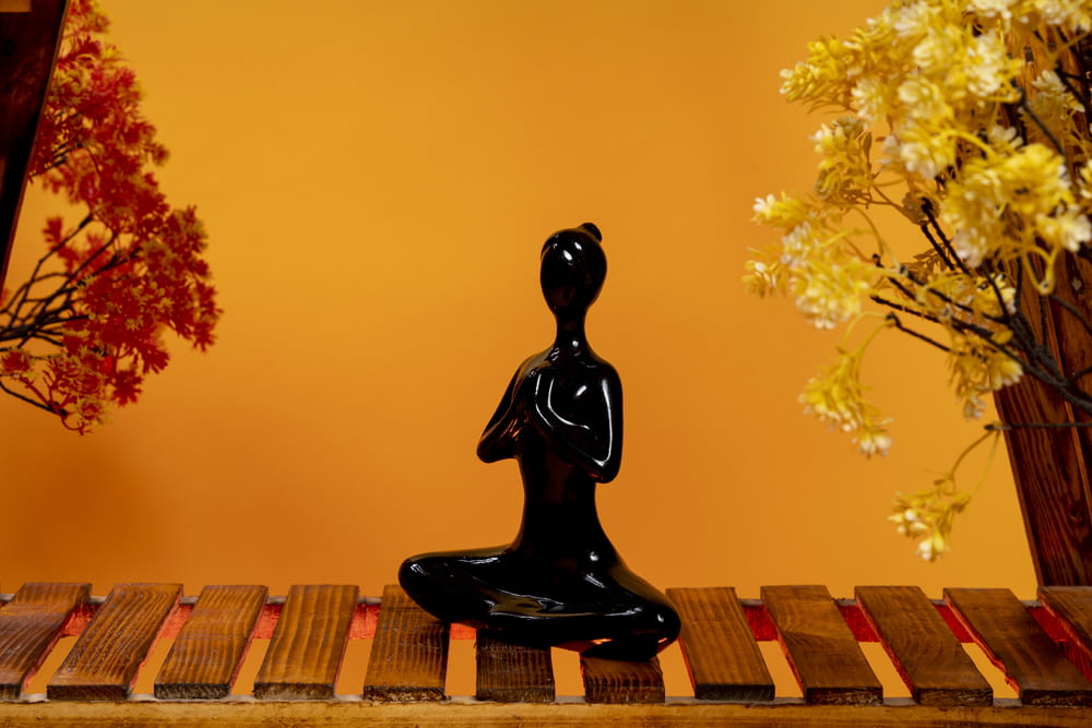 a black buddha statue sitting on a wooden table