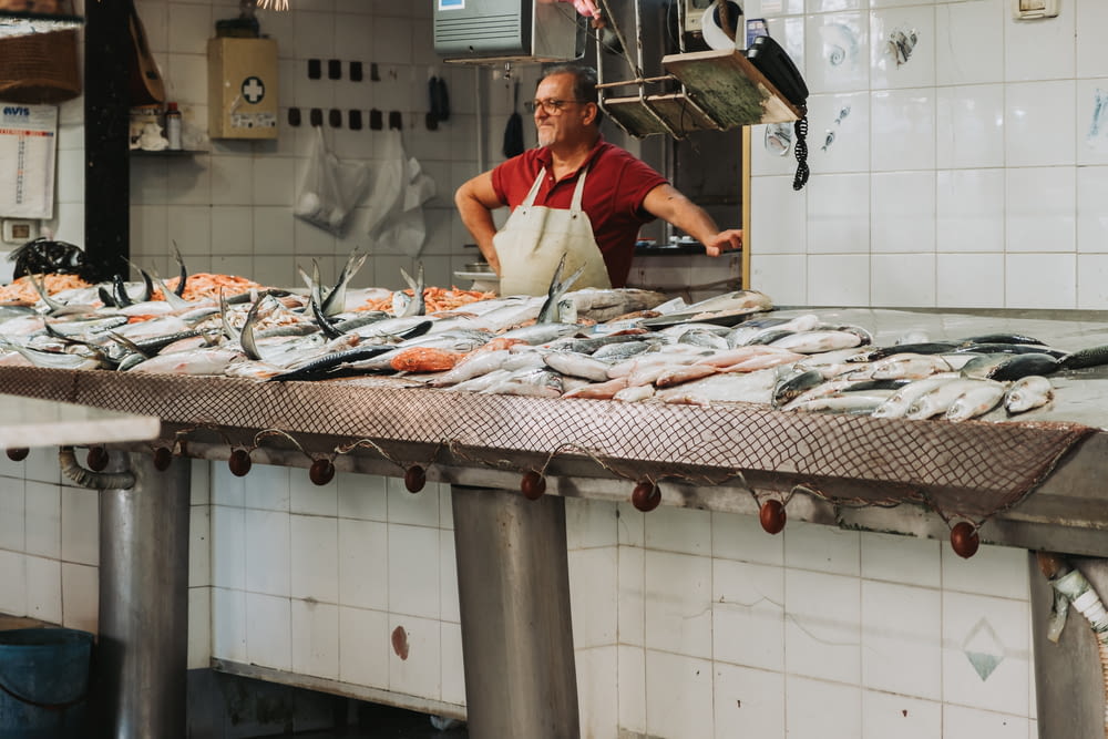 a man standing in front of a counter filled with fish