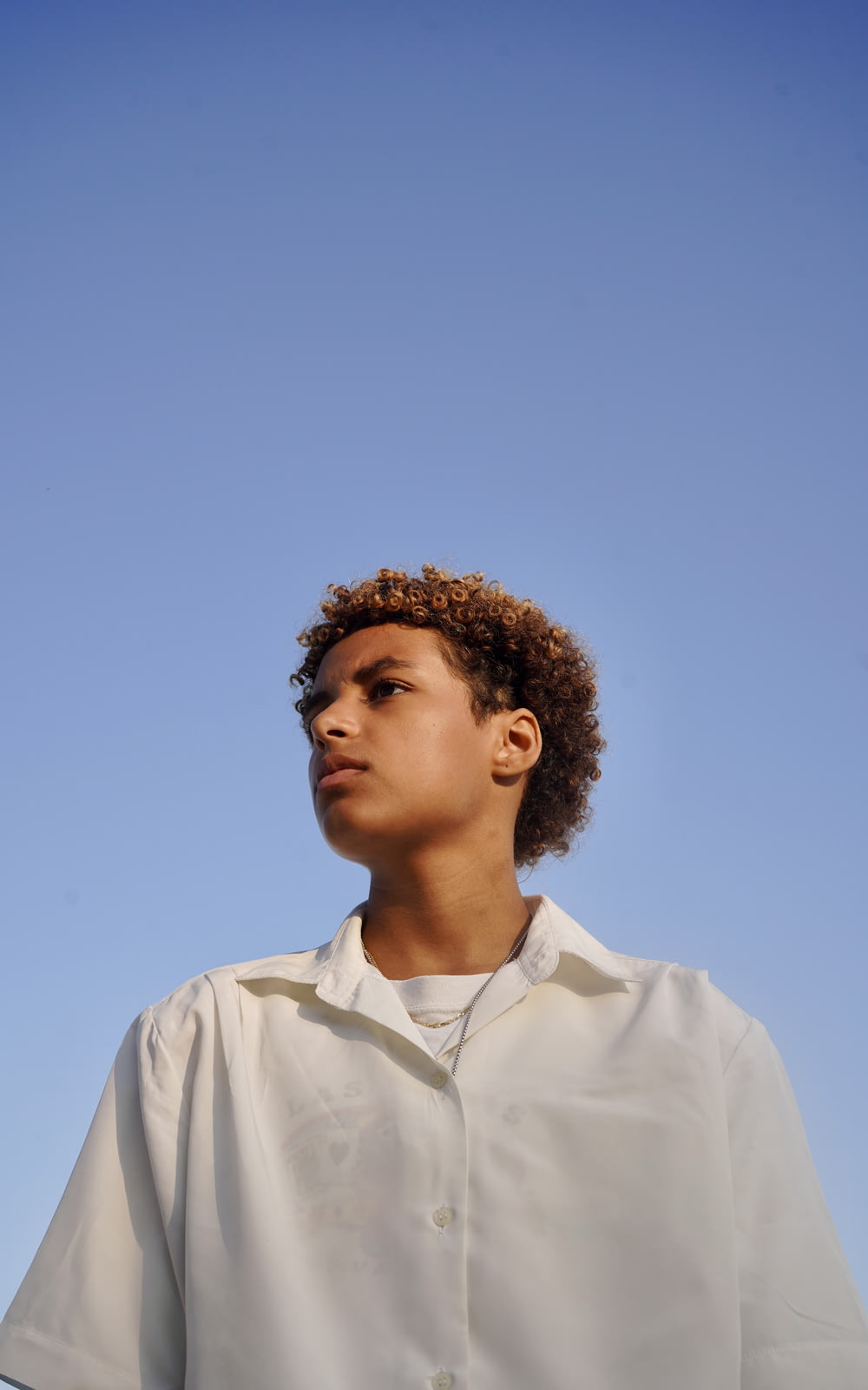a boy in a white shirt looking up at the sky