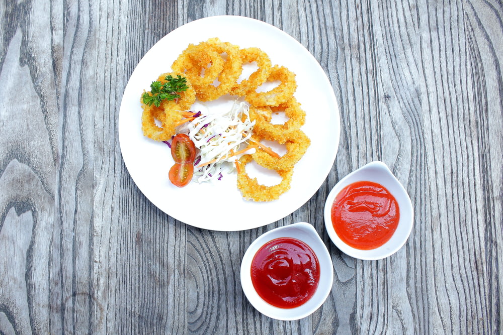 a white plate topped with onion rings and ketchup