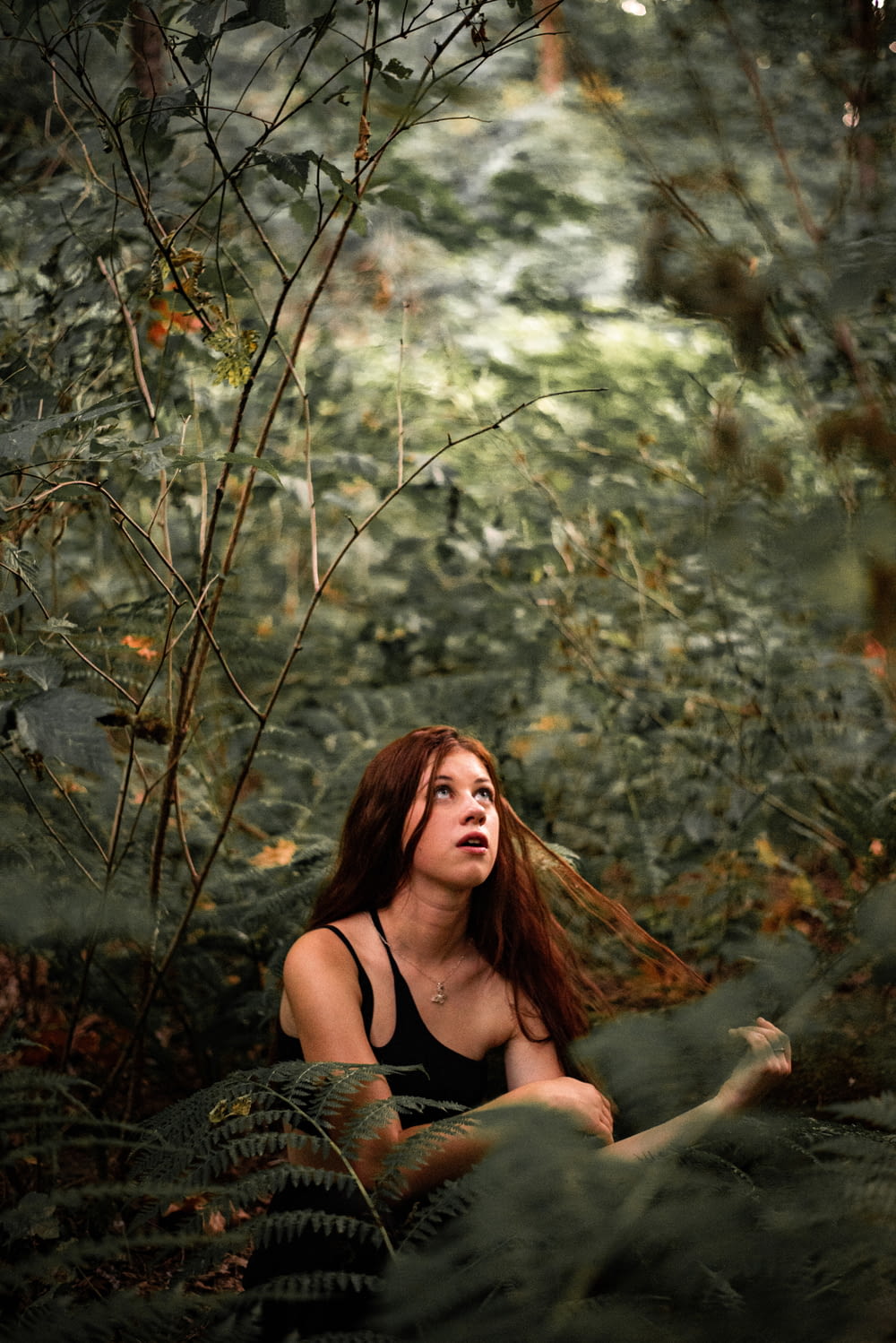 a woman sitting in the middle of a forest