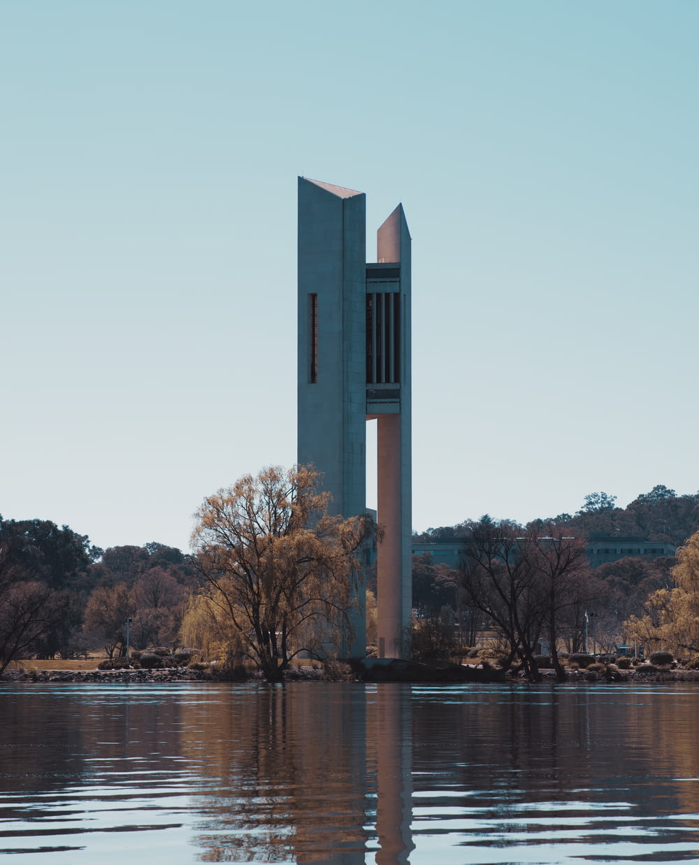a tall tower sitting on top of a lake next to a forest