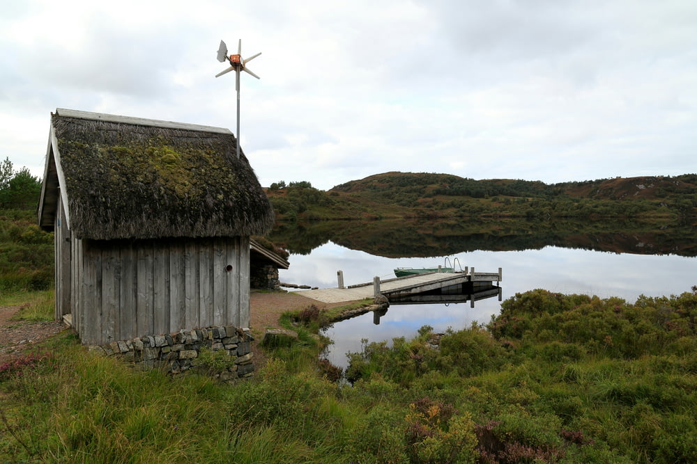 a small house with a thatched roof next to a body of water