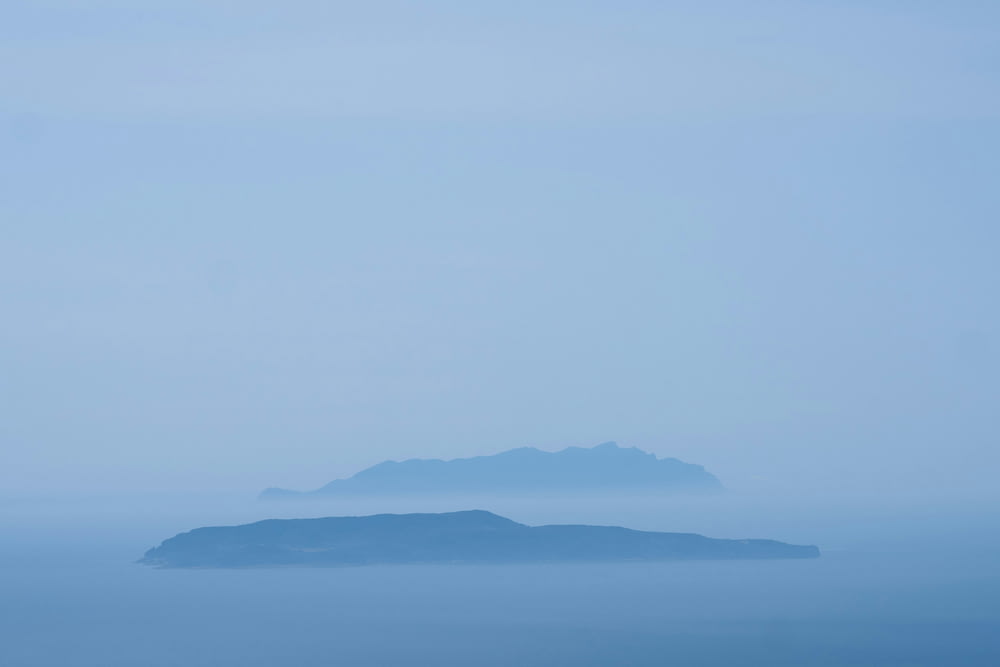 an island in the middle of the ocean on a foggy day