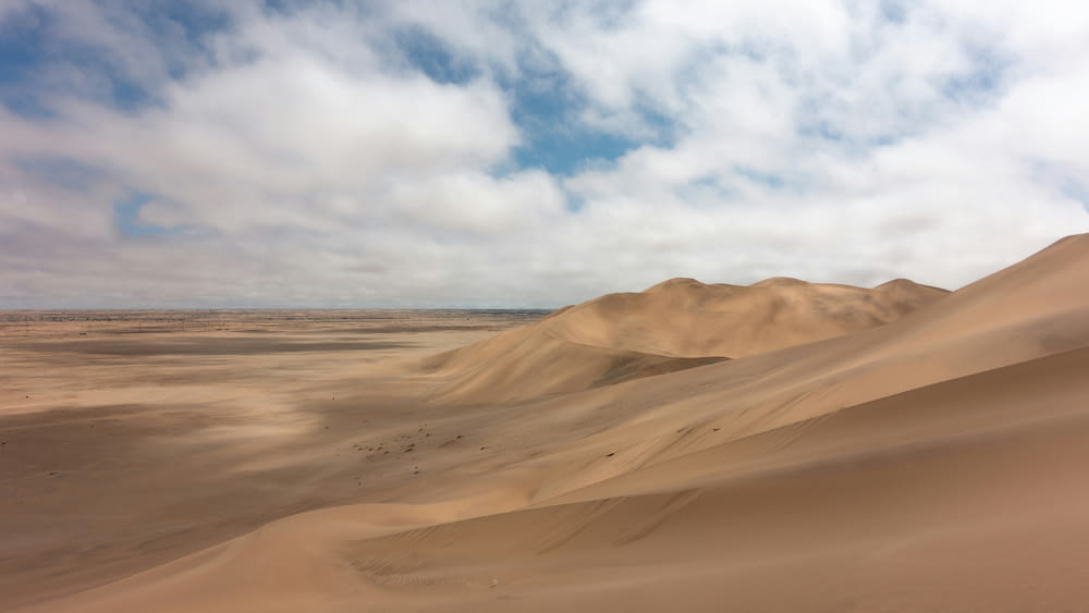 a desert landscape with sand dunes and clouds