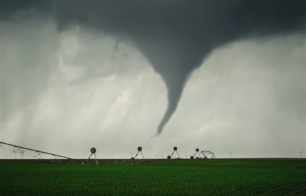 a large tornado is in the sky over a green field