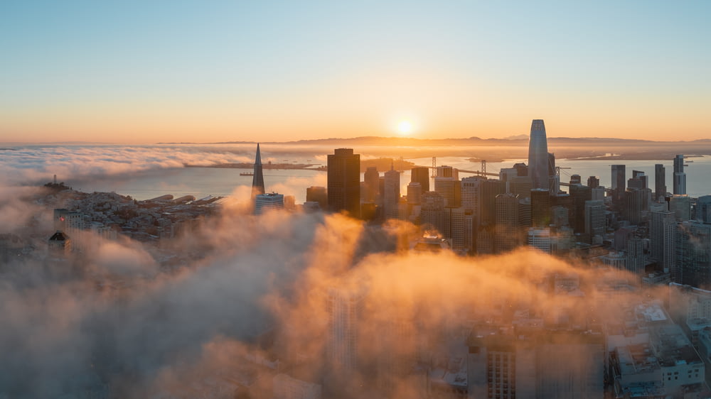 a view of a city in the clouds at sunset