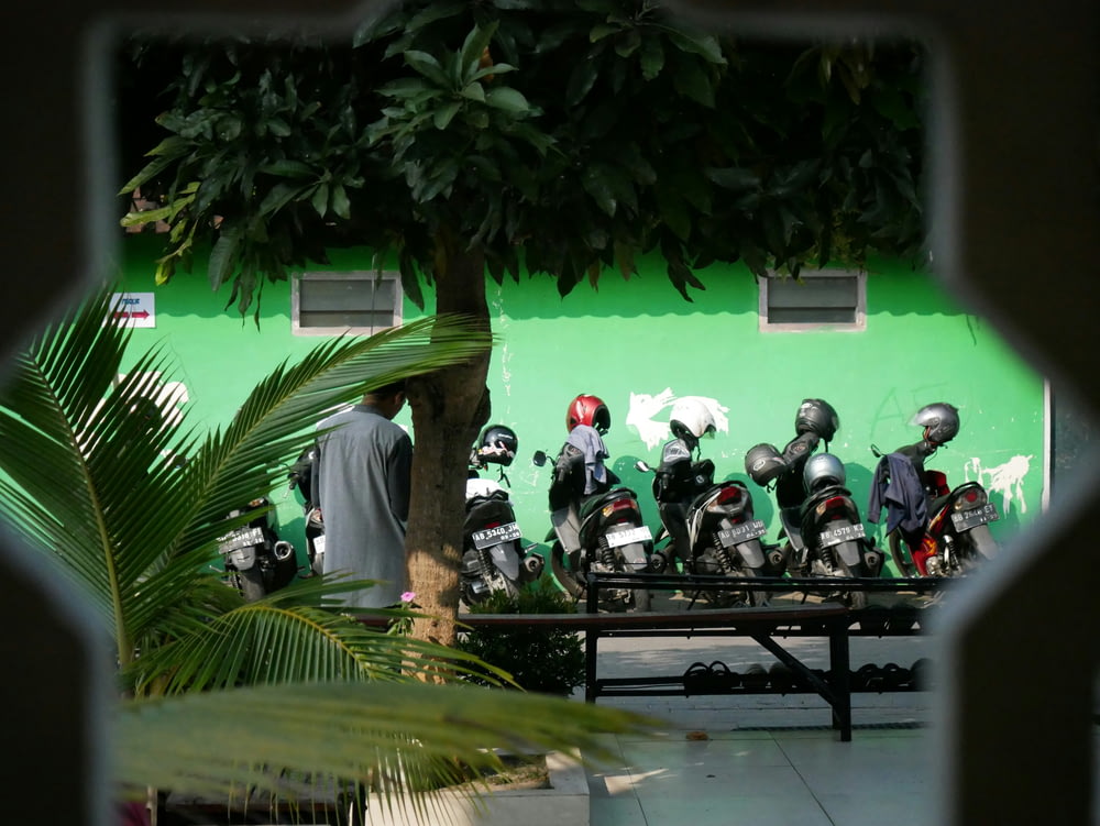 a group of motorcycles parked next to a green wall