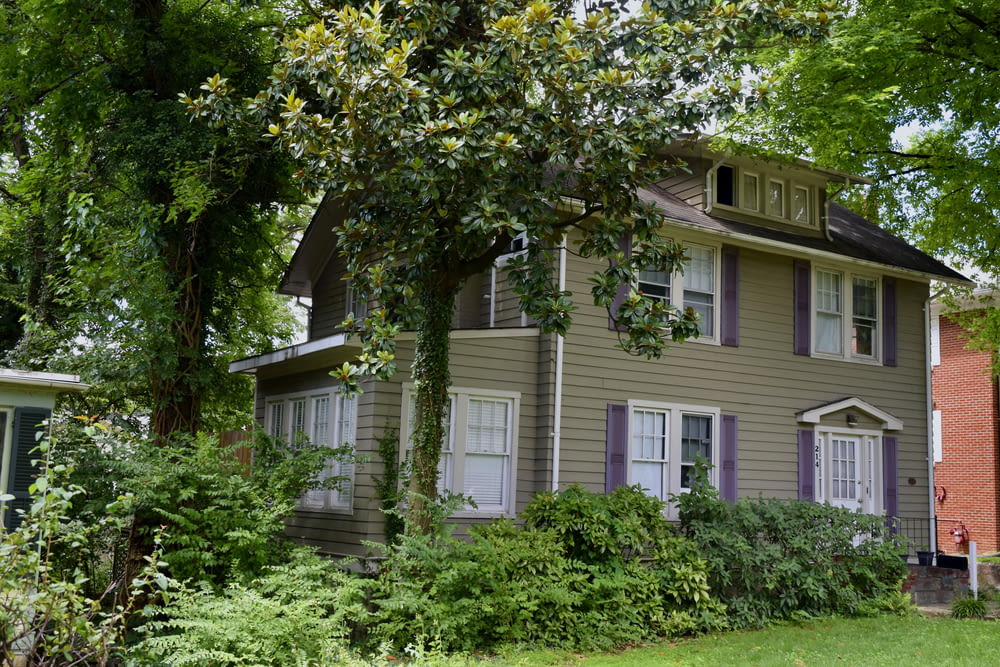a brown house with purple shutters and trees